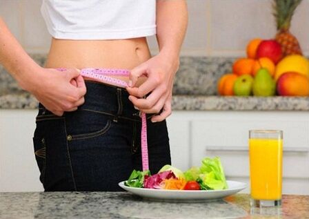 Girl losing weight by diet measuring waist size